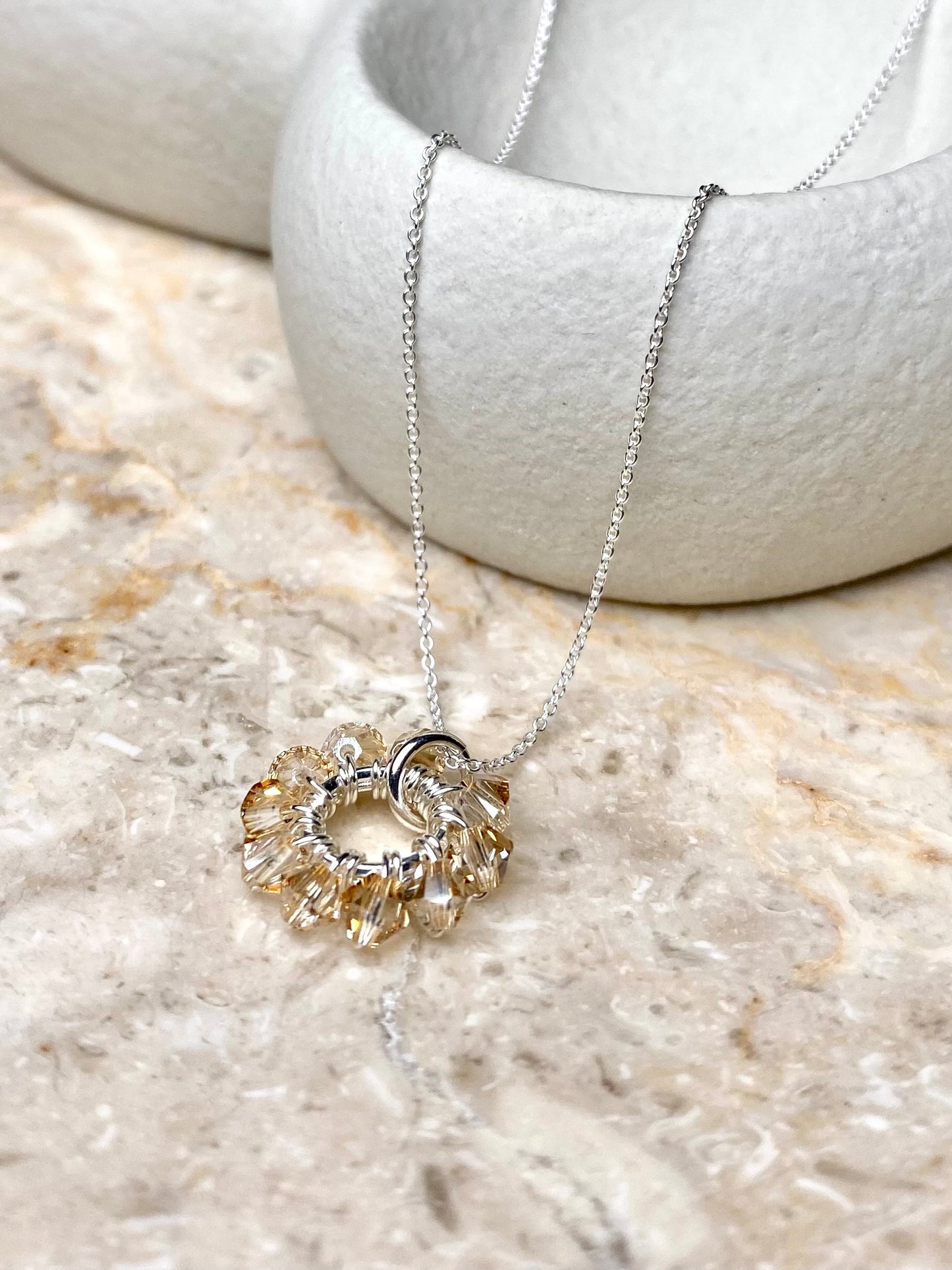 Minimalistinen hopeinen kaulakoru, jossa on siro ketju ja yksinkertainen ja neutraalin värinen riipus