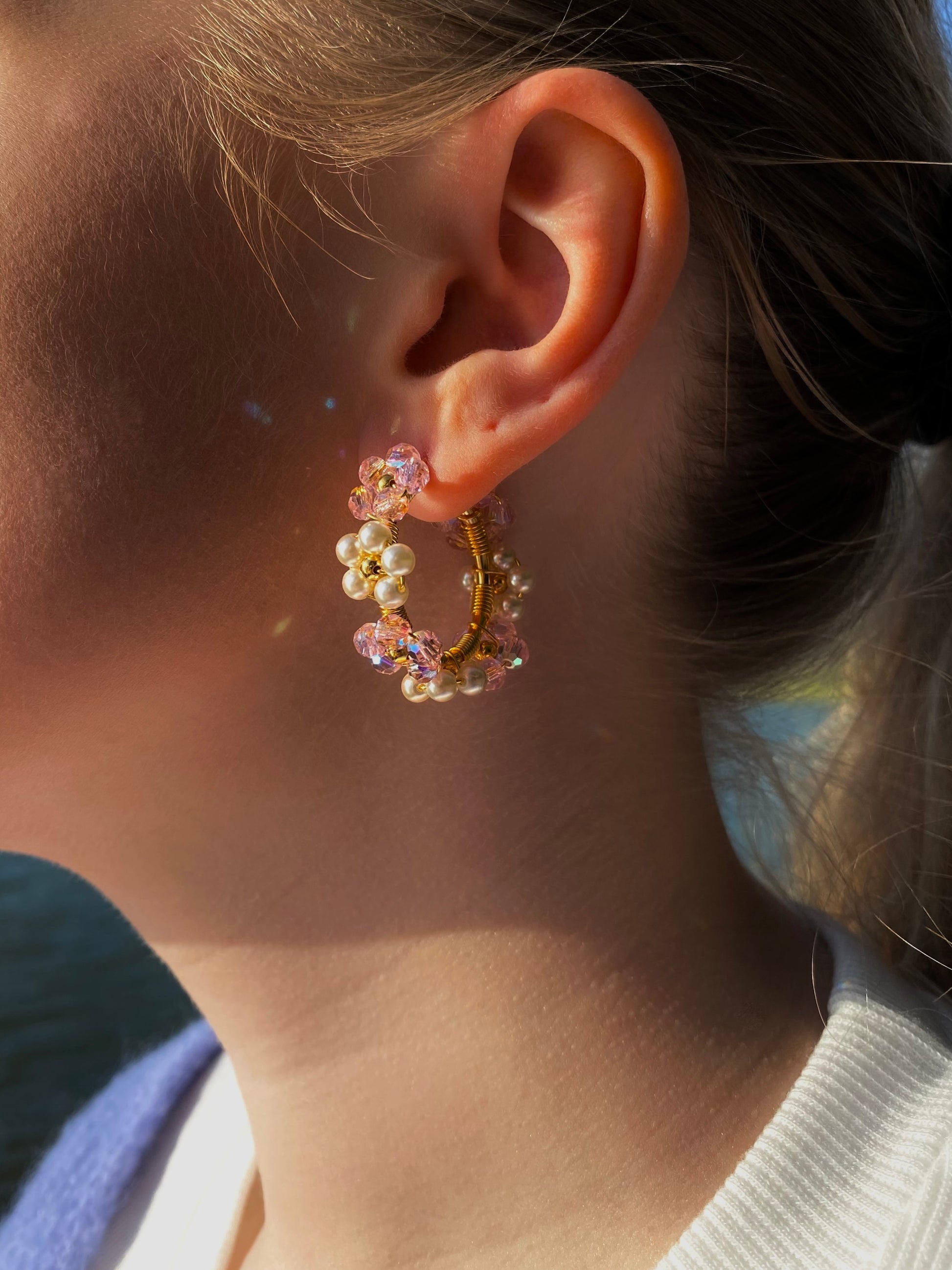 Kukkakorvakorut vaaleanpunaisilla ja helmiäisen väirillä kristalleilla