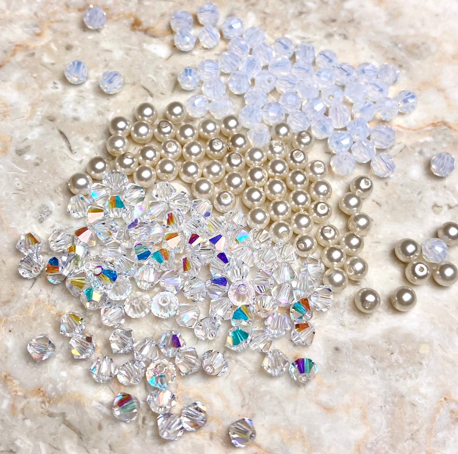 Valkoisia, kirkkaita ja helmiäisen värisiä kristallihelmiä kasassa