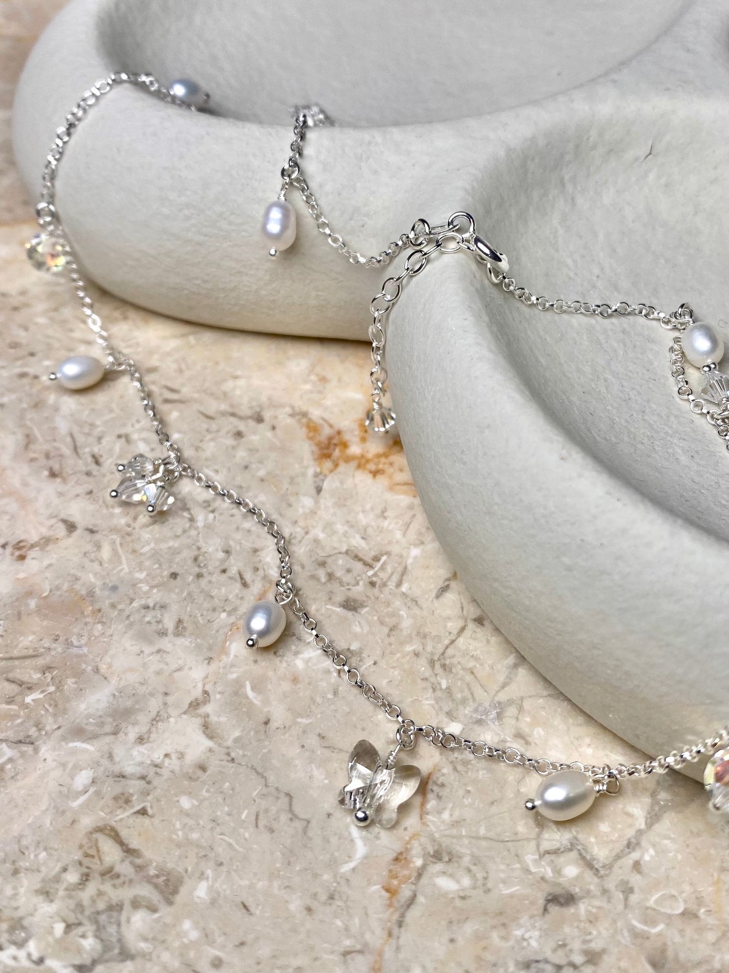 Kotimainen hopeakoru, jossa kaulakoruketjuun on kiinnitetty pieniä kristalli- ja helmiriipuksia