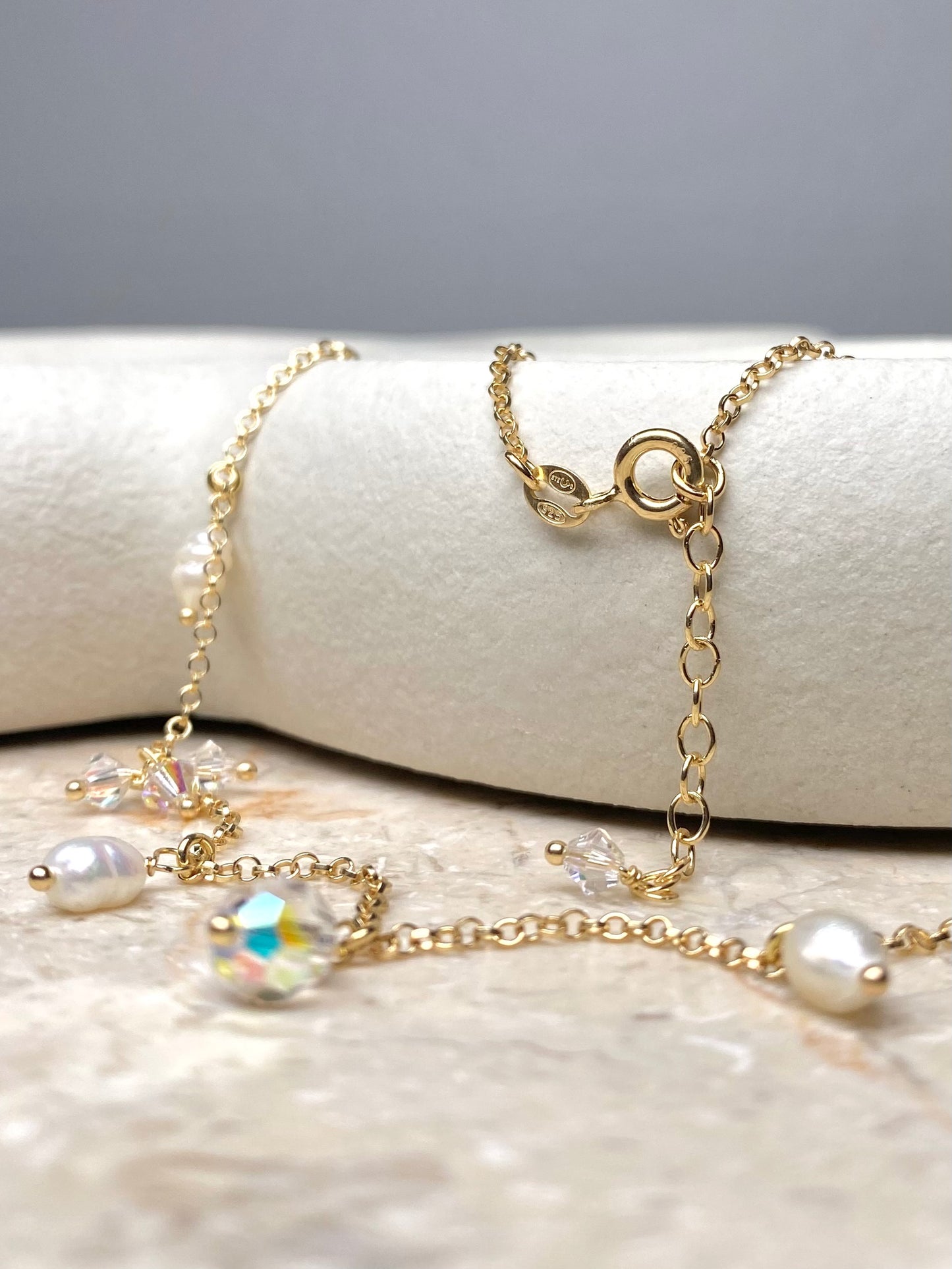 Lähikuva kullatusta hopeakorusta, jossa roikkuu kristalleja ja helmiä