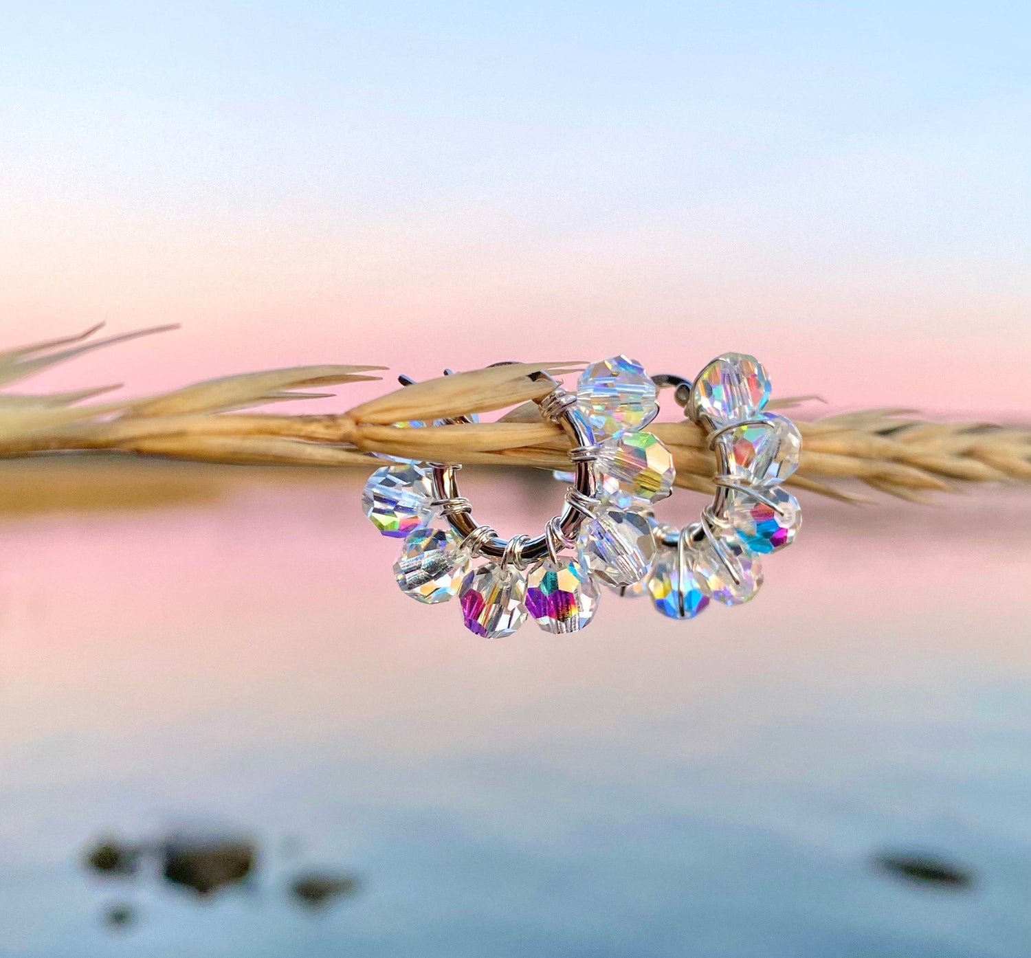 Hopeiset korvakorut ja taustalla vaaleanpunainen auringonlasku