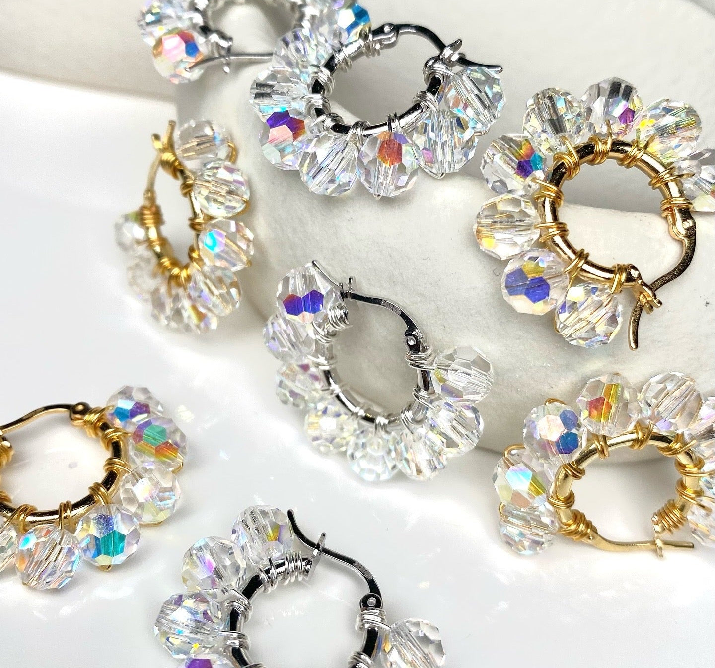 Hopeisia ja kullattuja hopeisia korvakoruja kirkkailla pyöreillä kristalleilla