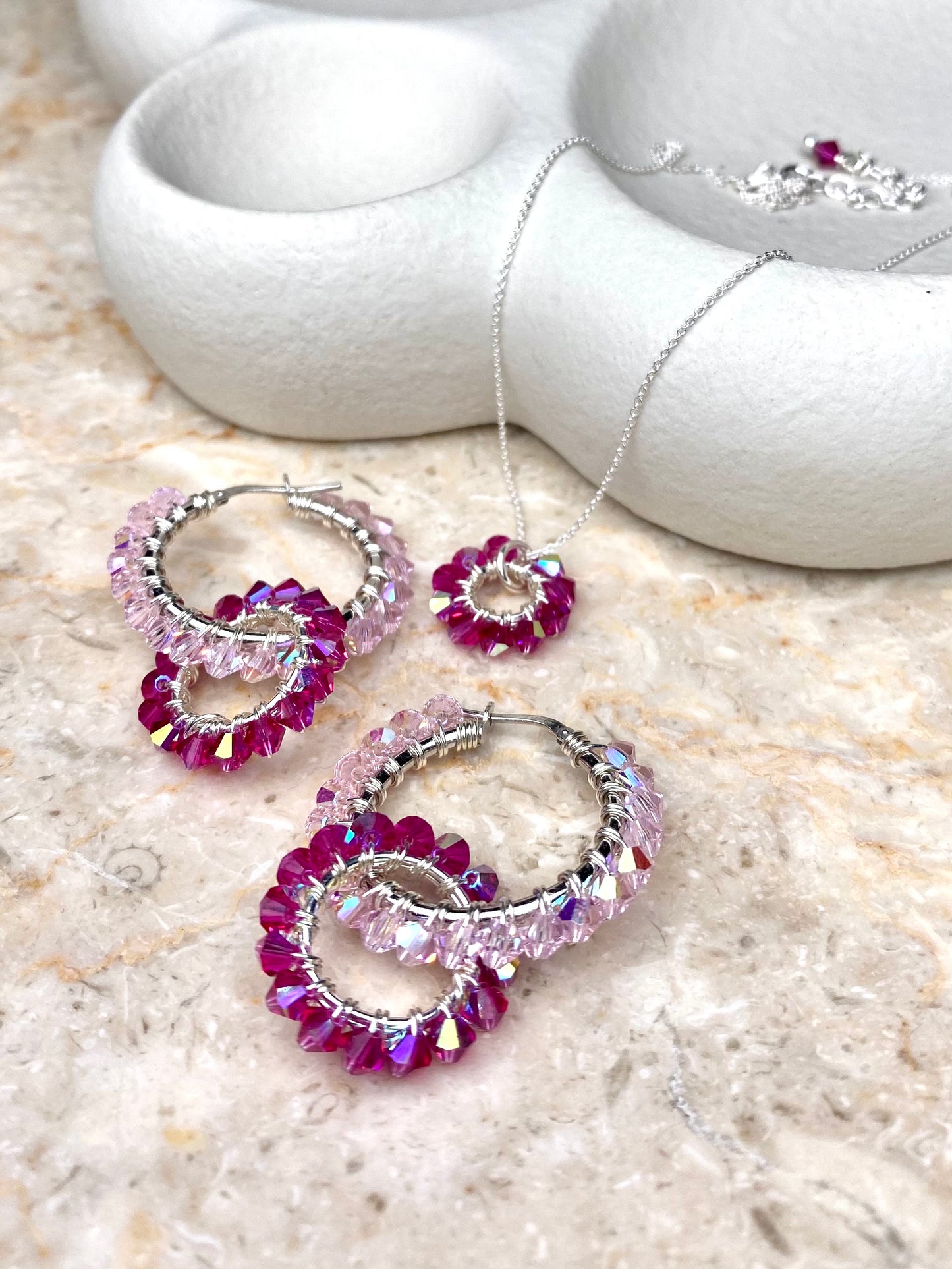 Vaaleanpunainen kaulakoru ja korvakorut, jotka on tehty hopeasta