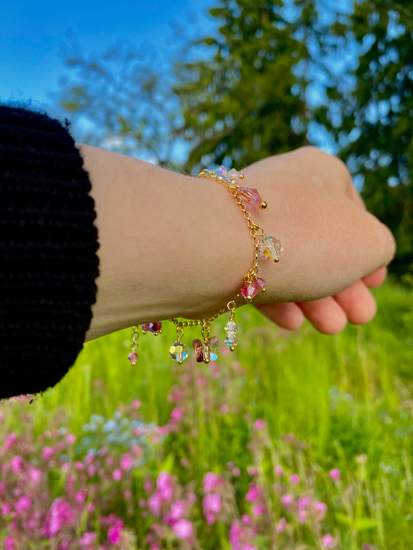 Kultainen vaaleanpunainen riipusrannekoru mallin ranteessa