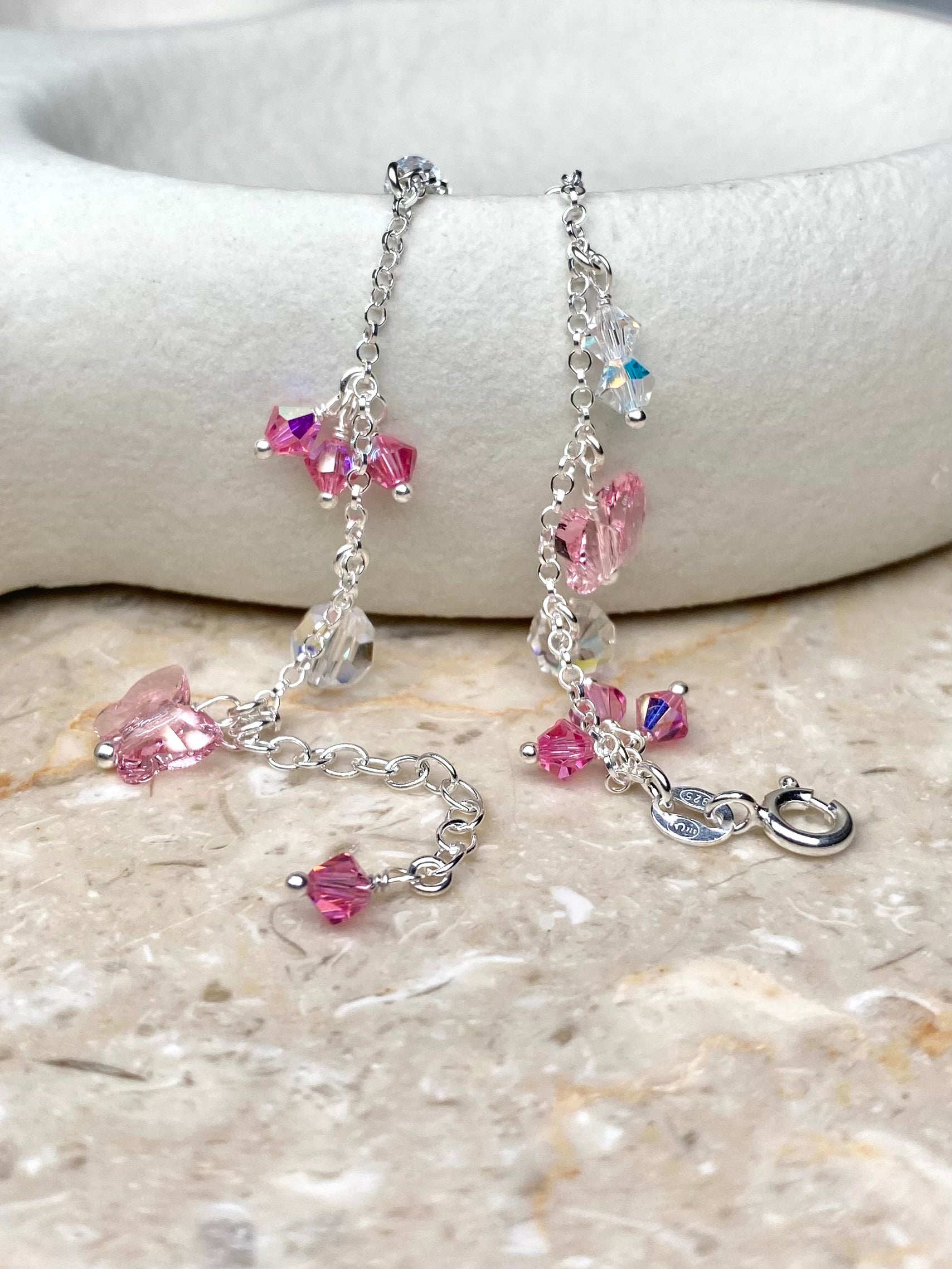 Hopeinen rannekoru jossa on vaaleanpunaisia kristalleja