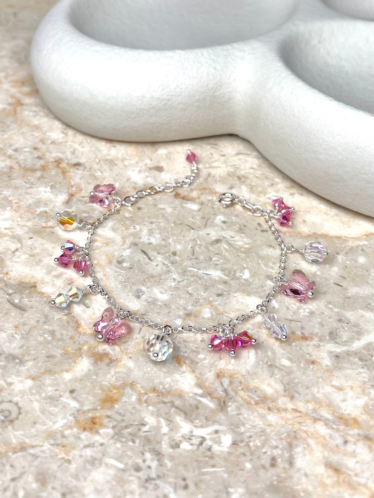 Kierrätyshopeasta tehty rannekoru, jossa on vaaleanpunaisia ja kirkkaita kristallikoristeita