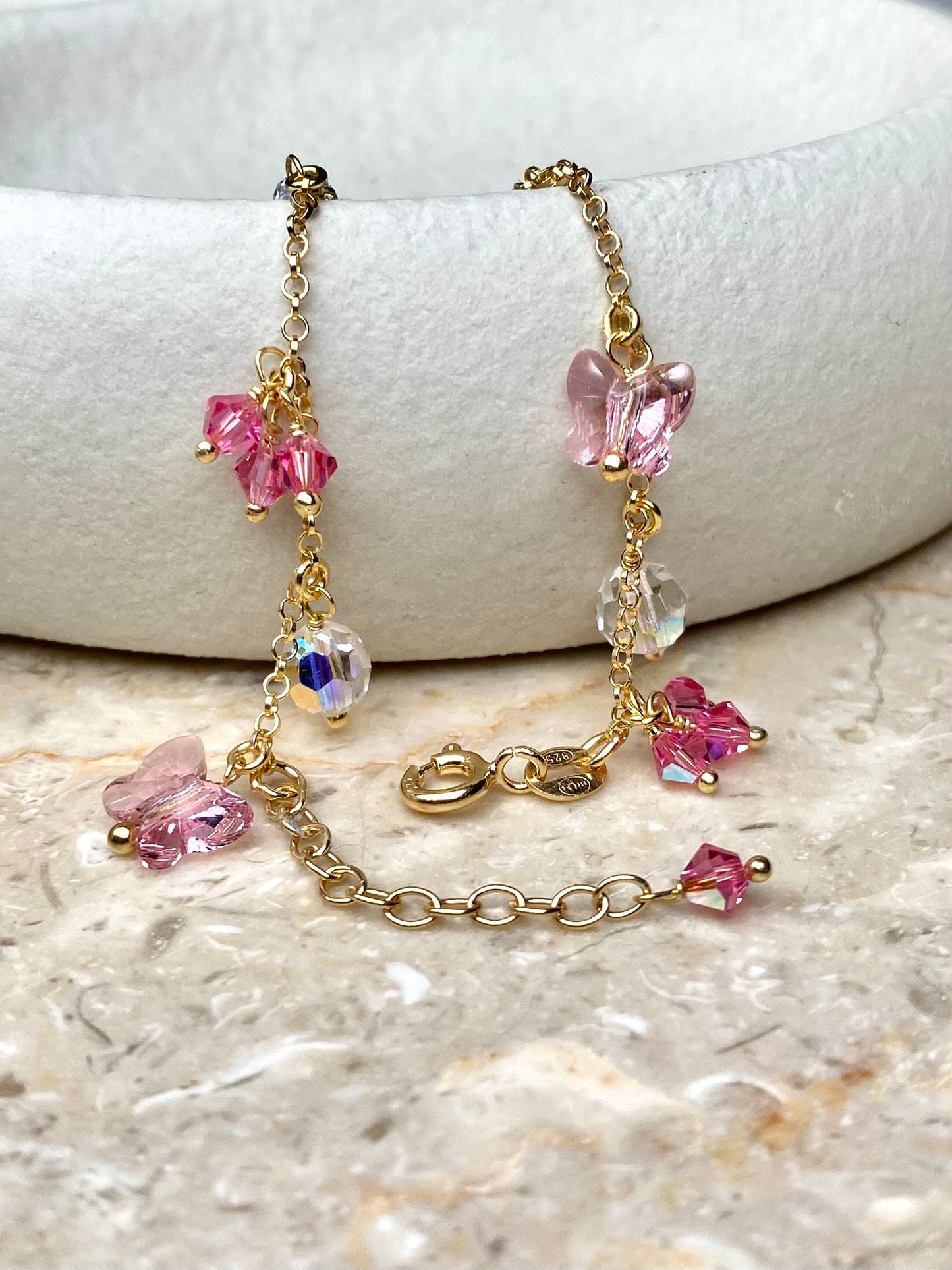 Kultainen rannekoru vaaleanpunaisilla yksityiskohdilla