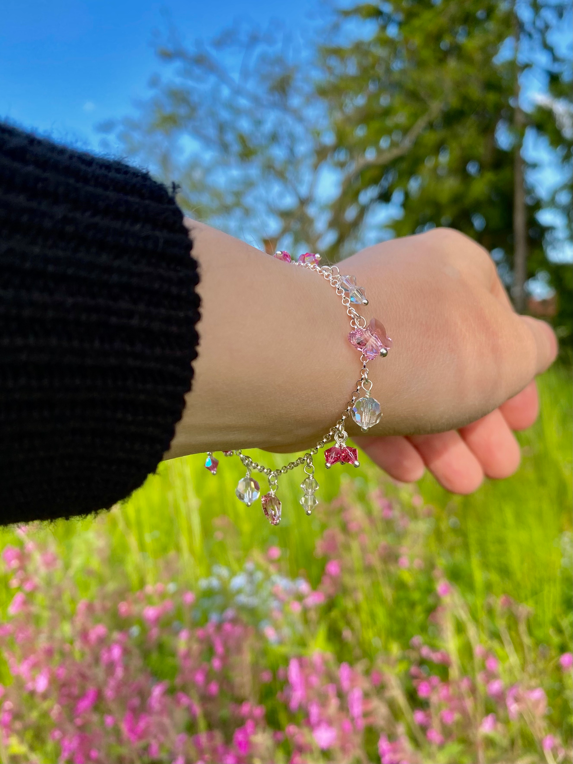 Hopeinen vaaleanpunainen riipusrannekoru mallin ranteessa