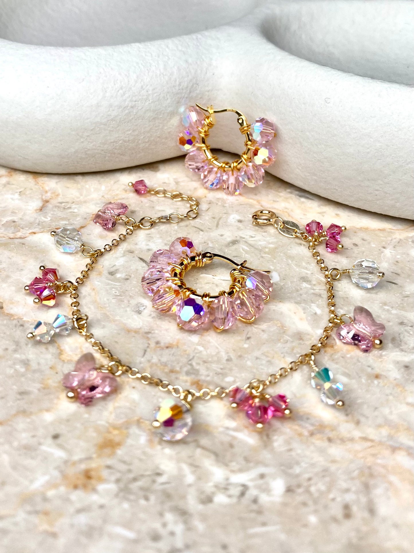 Vaaleanpunainen korusetti, johon kuuluvat kullatusta hopeasta tehdyt korvakorut ja rannekoru