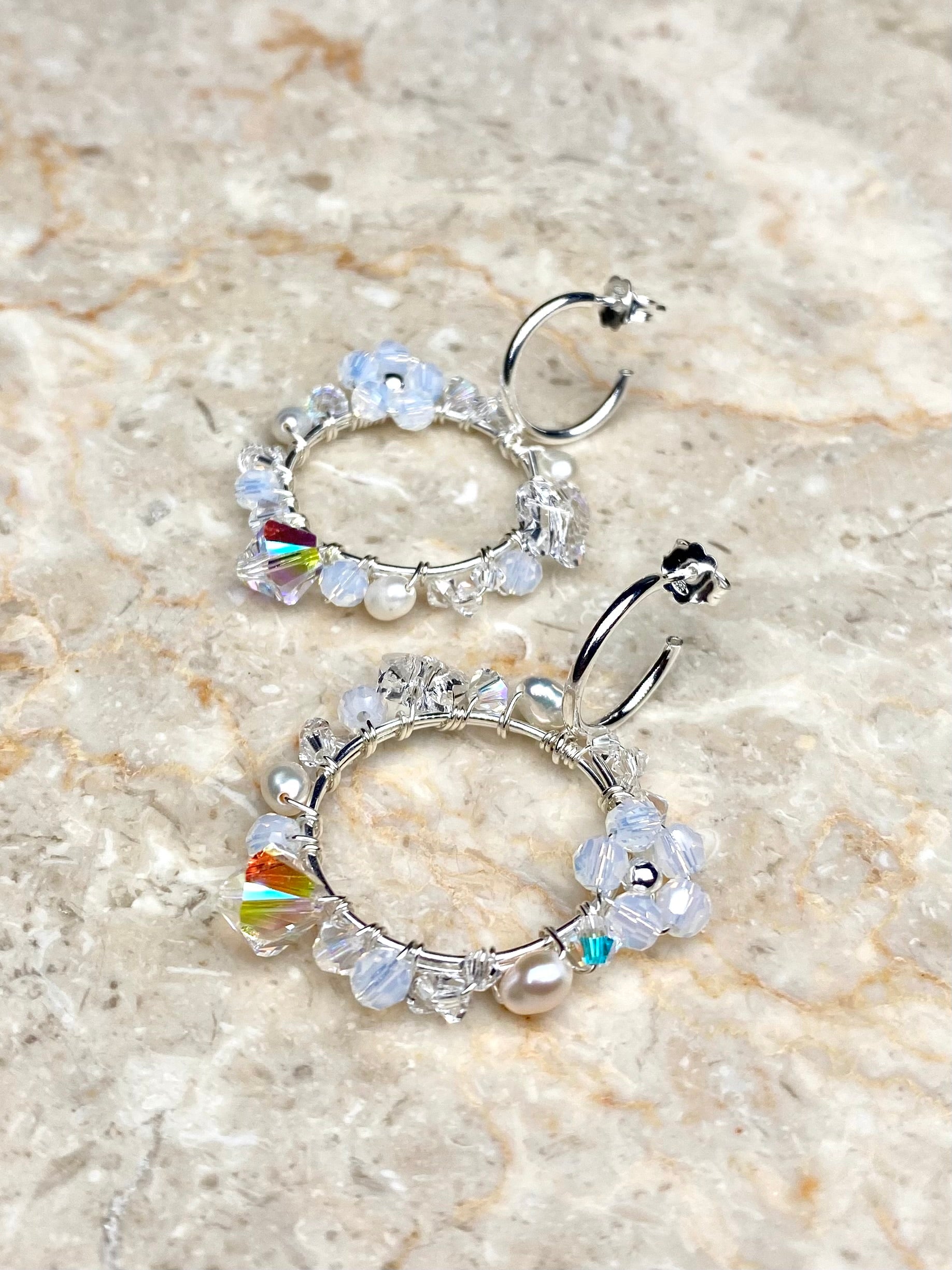 Näyttävät hopeiset korvakorut, joissa on valkoisia kristalleja ja makeanvedenhelmiä.