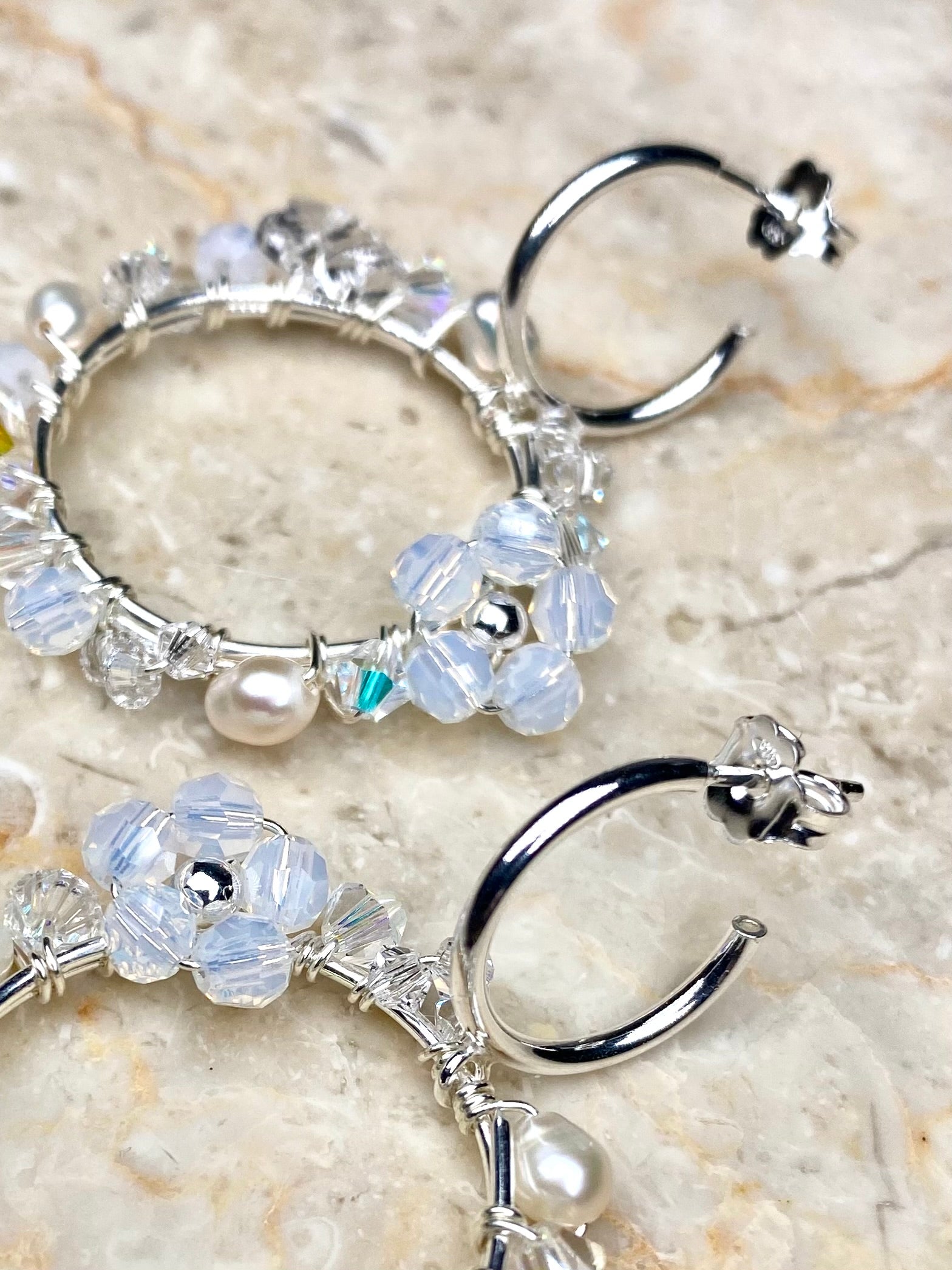 Lähikuva käsintehdyistä hopeisista kukkakorvakoruista