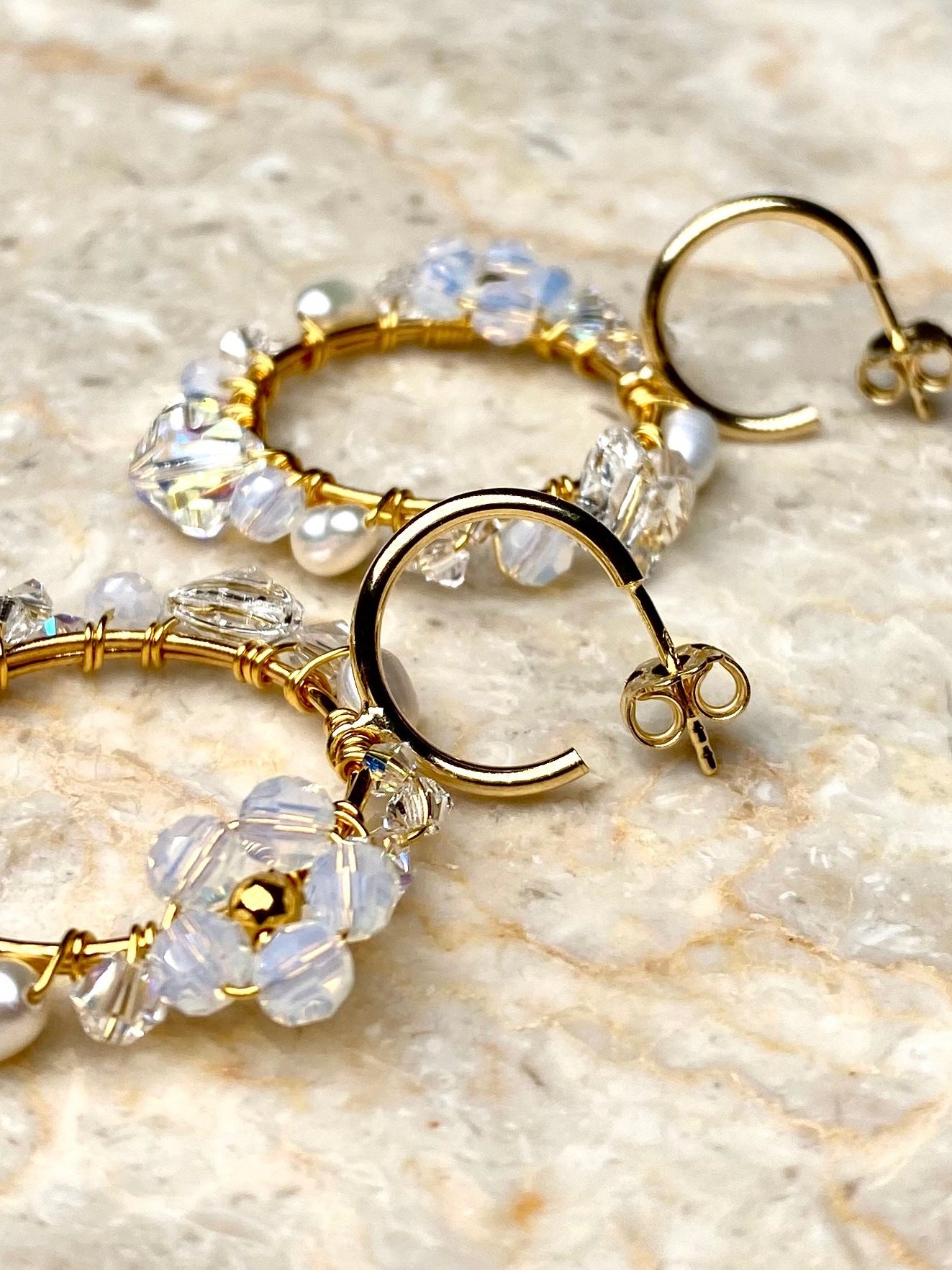 Lähikuva käsintehdyistä korvakoruista, joissa on valkoisia kristalleja ja makeanvedenhelmiä