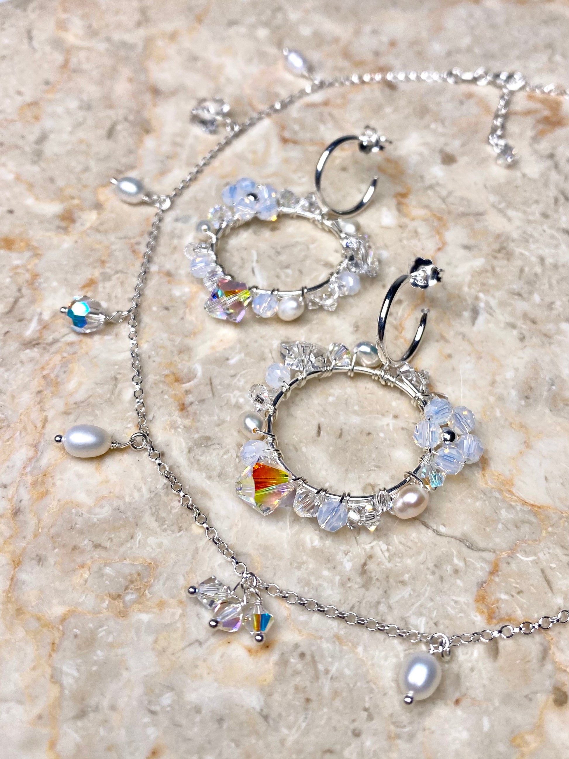 Hopeasta tehty näyttävä korusetti, jossa on valkoisia kristalleja ja helmiä. 