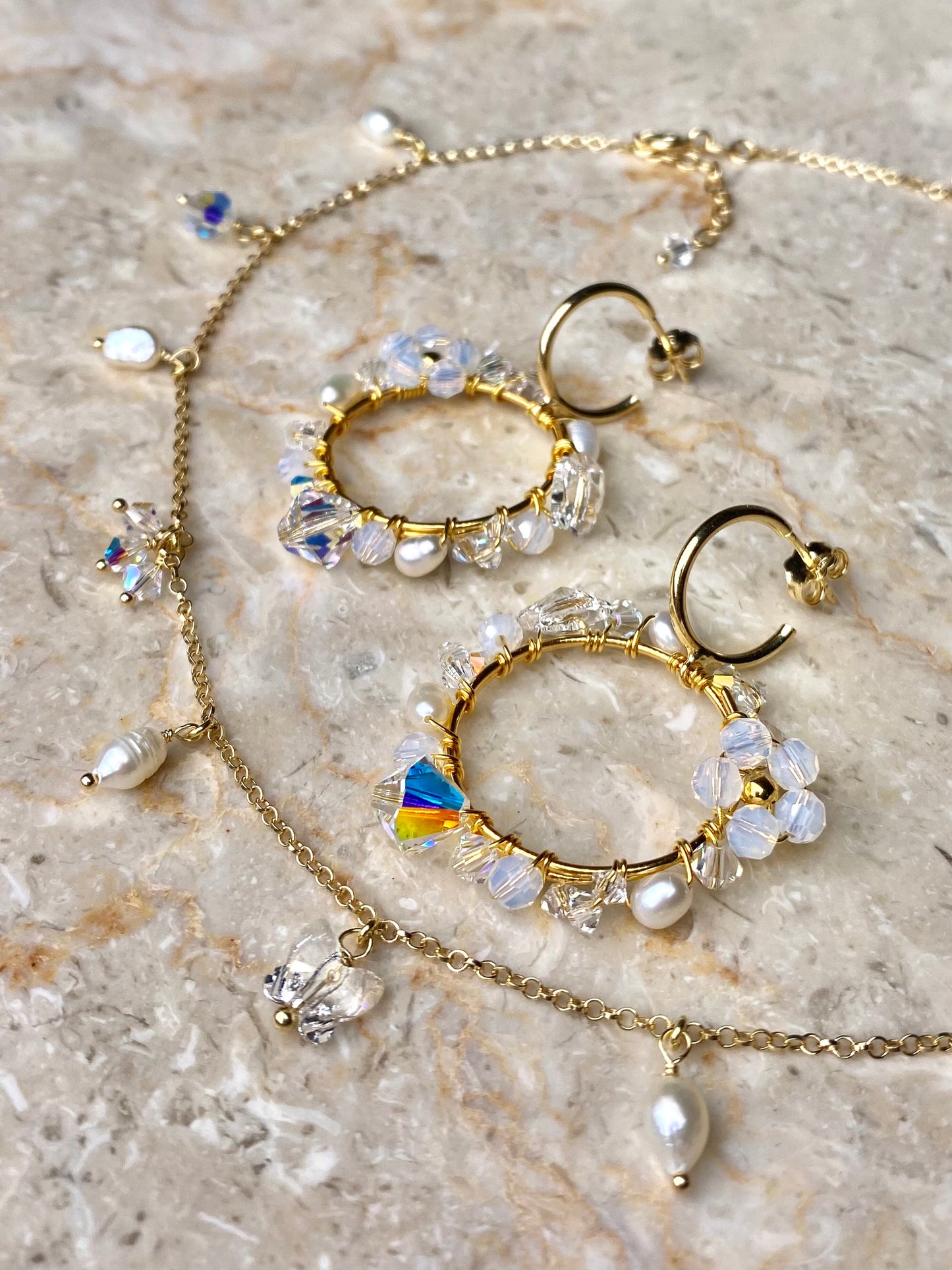 Kullatusta hopeasta käsintehty korusetti, jossa on valkoisia kristalleja ja makeanvedenhelmiä. Näyttävät korut.