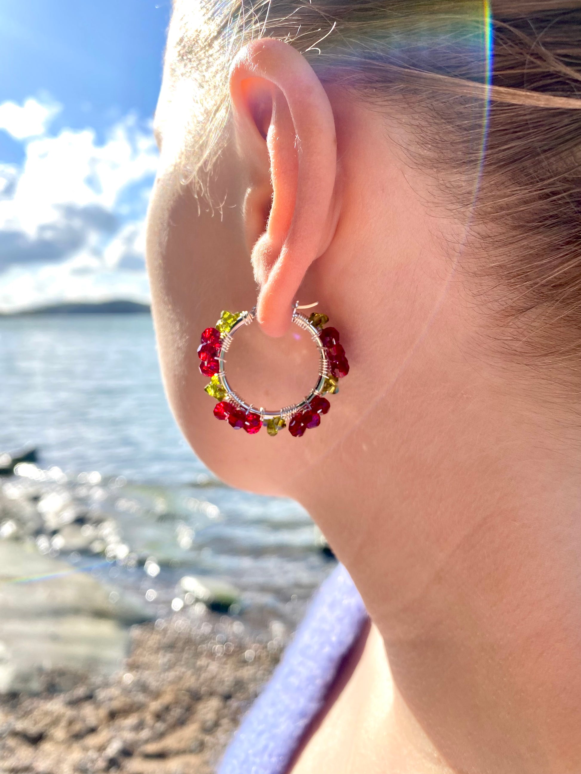 Tummanpunaiset kukkakorvakorut mallin korvassa, hopea