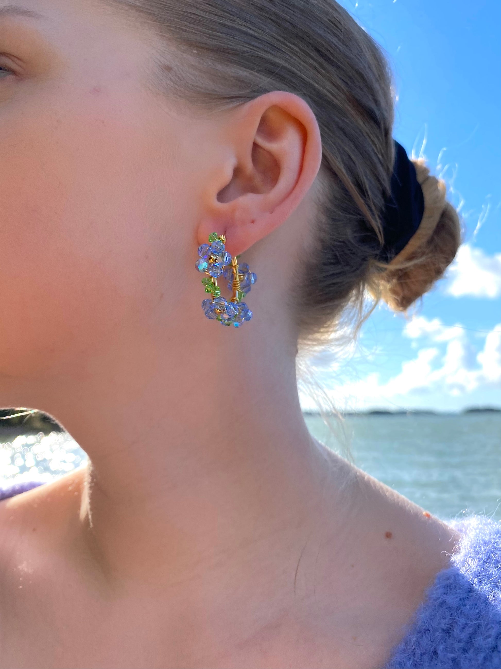 Vaaleansiniset kukkakorvakorut mallin korvassa