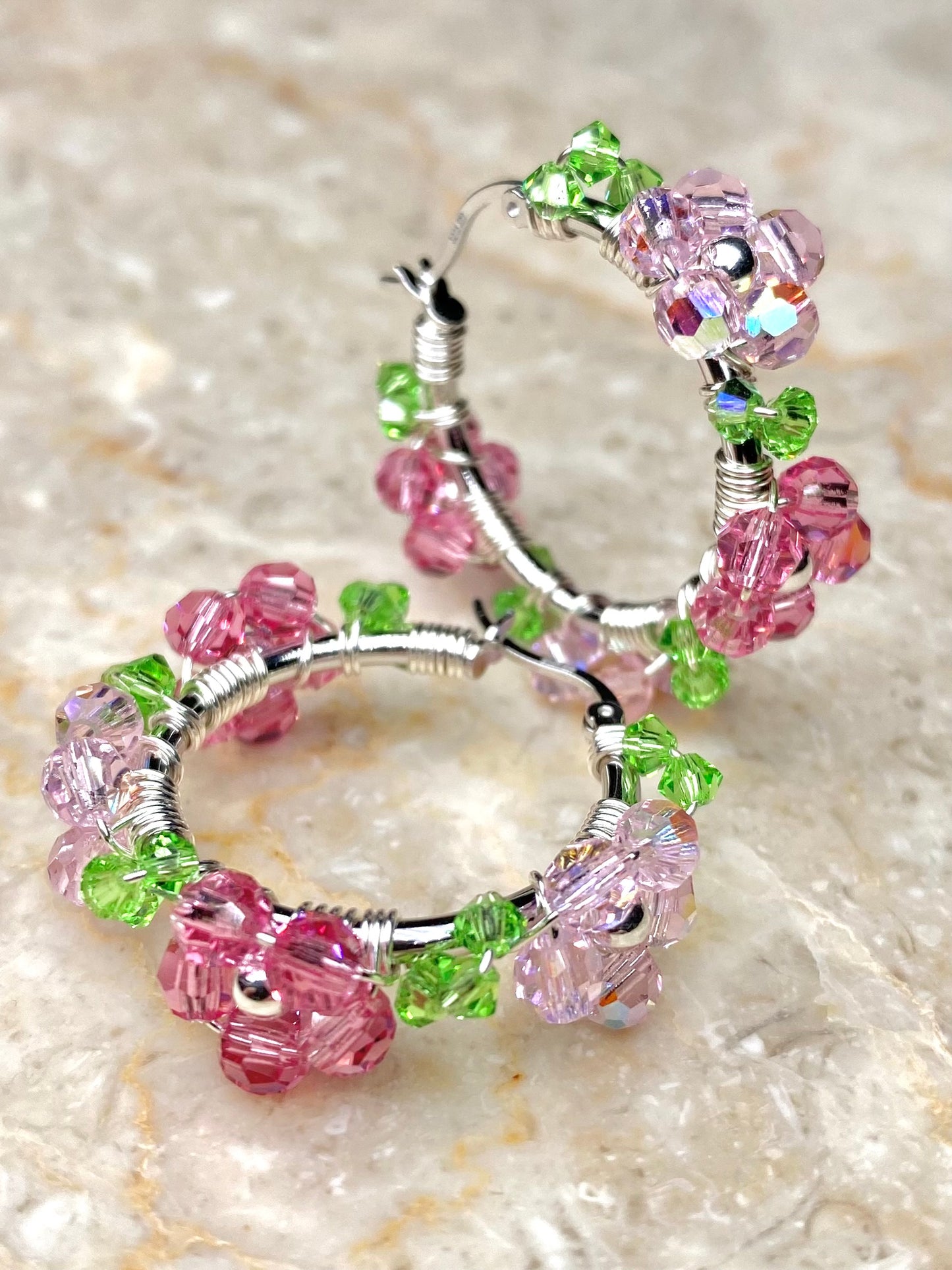 Vaaleanpunaisilla kukilla koristellut hopeiset korvakorut