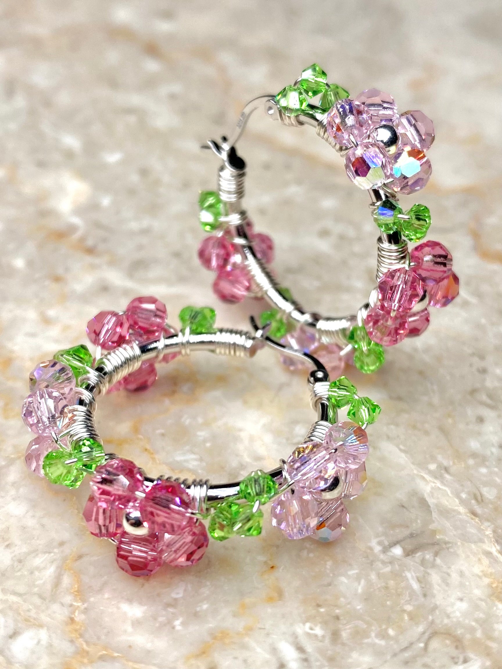 Vaaleanpunaisilla kukilla koristellut hopeiset korvakorut