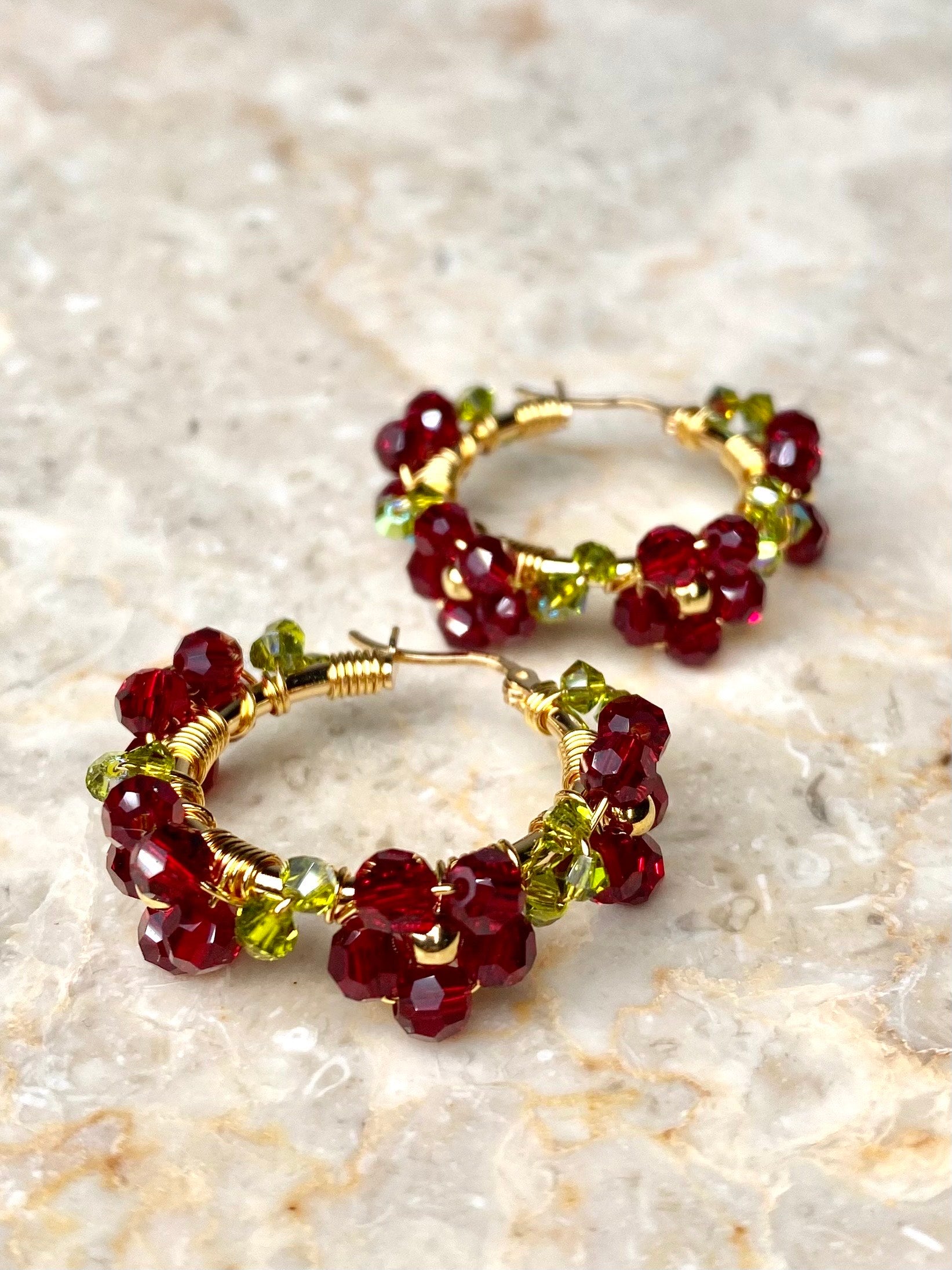 Tummanpunaisilla kukilla koristellut kultaiset rengaskorvakorut