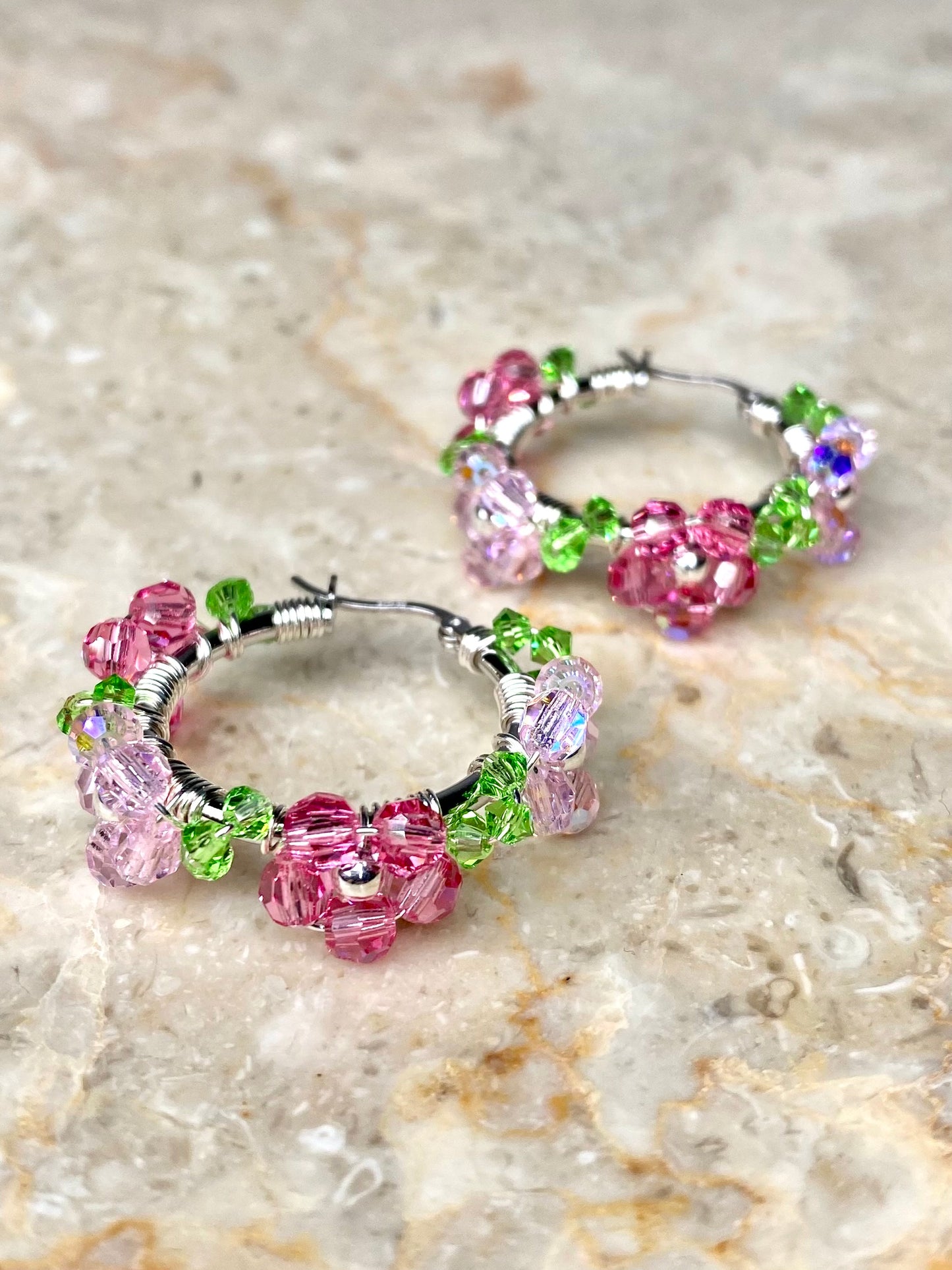 Hopeiset vaaleanpunaiset korvakorut, joissa on kimaltavia kristallikukkia