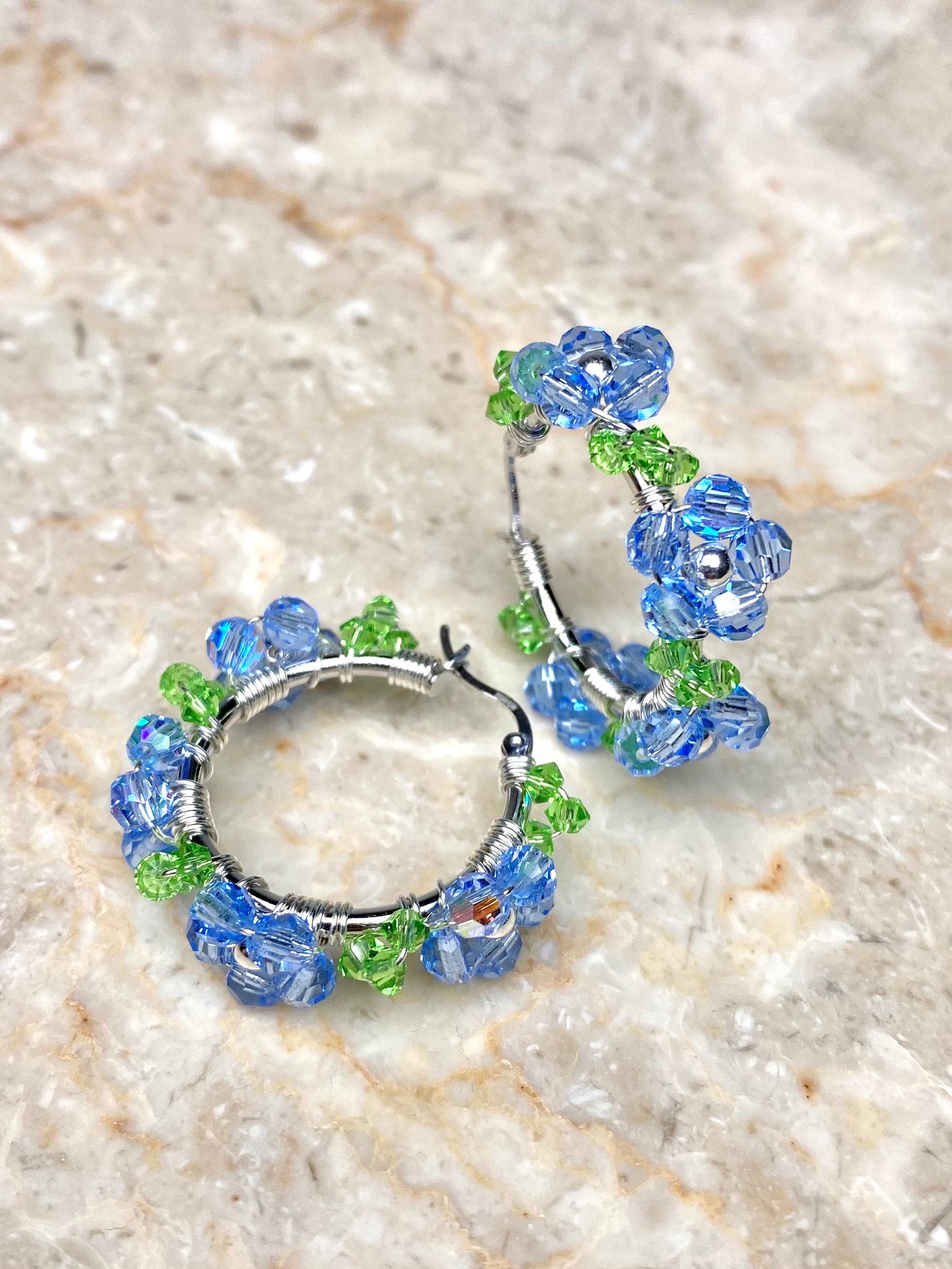 Lähikuva vaaleansinisistä kukkakorvakoruista, hopea