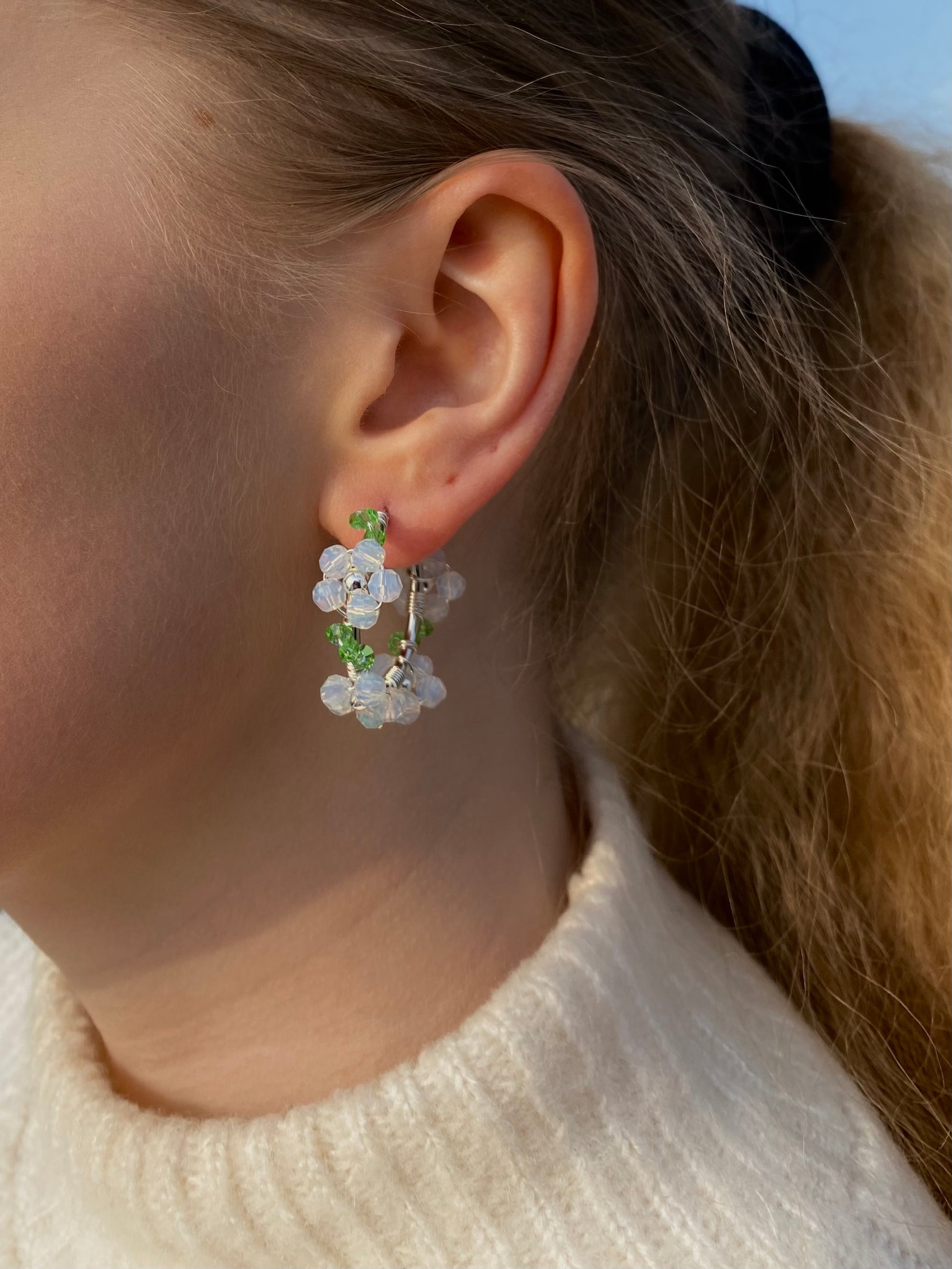 Valkoinen hopeinen kukkakorvakoru mallin korvassa