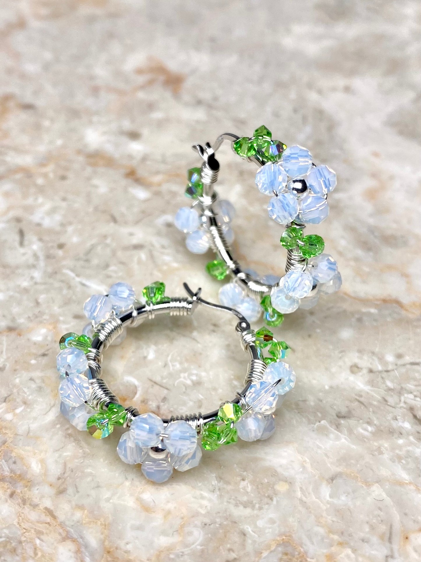 Hopeiset rengaskorvakorut valkoisilla kristallikukilla koristeltuna