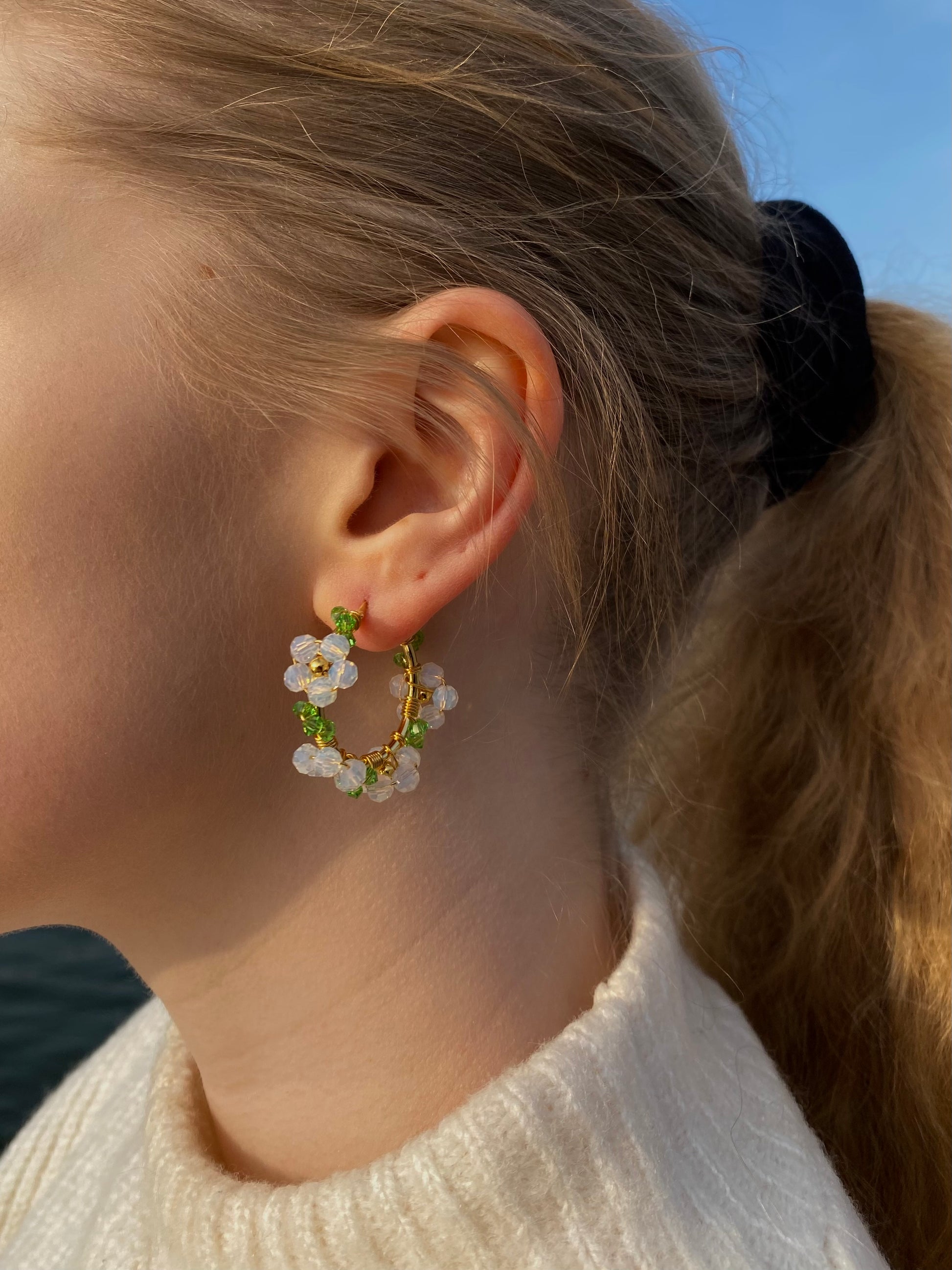 Valkoiset kristallikukkakorvakorut mallin korvassa, kullattu hopea