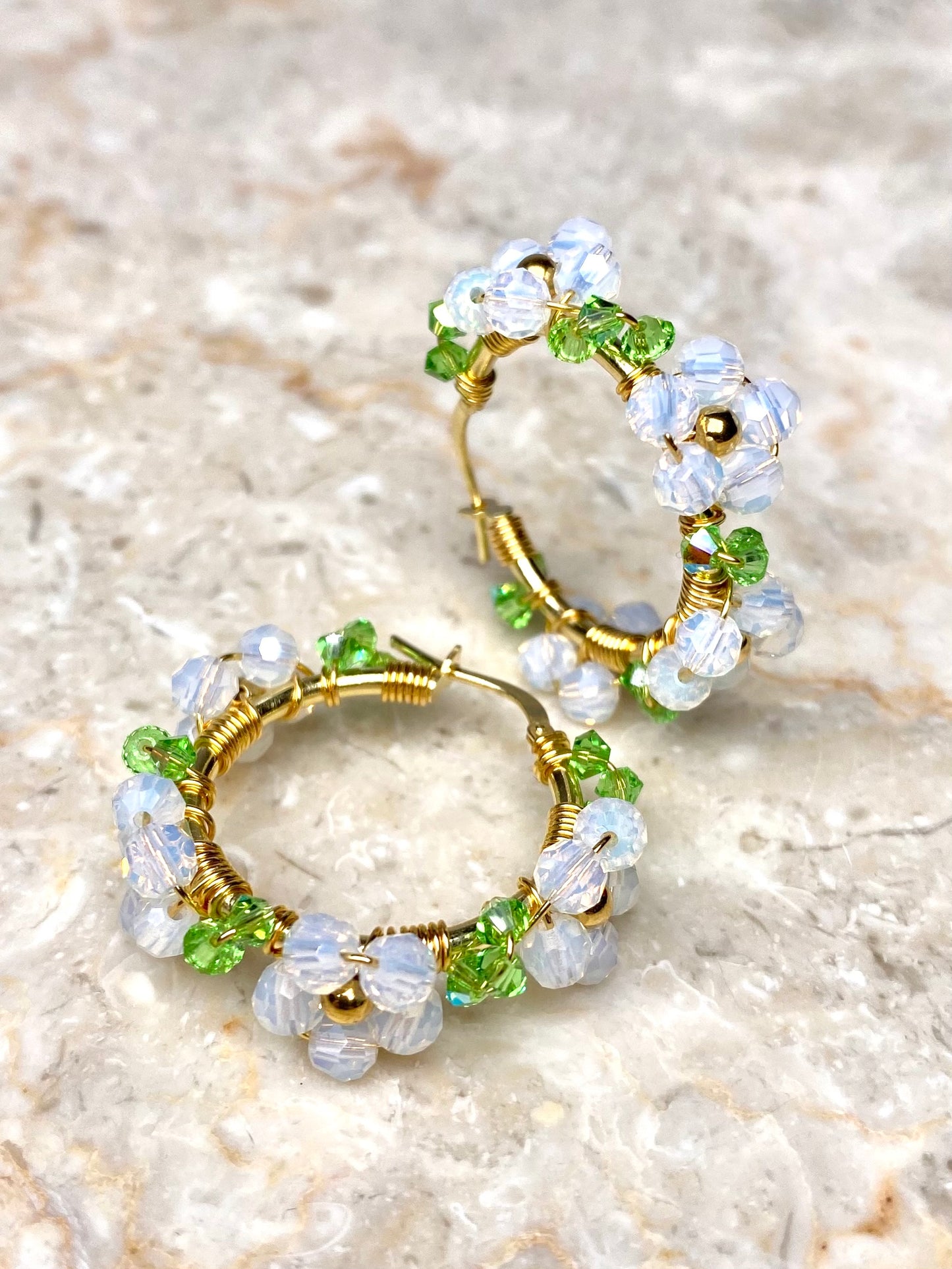 Valkoiset kultaiset rengaskorvakorut, koristeltu kukilla.