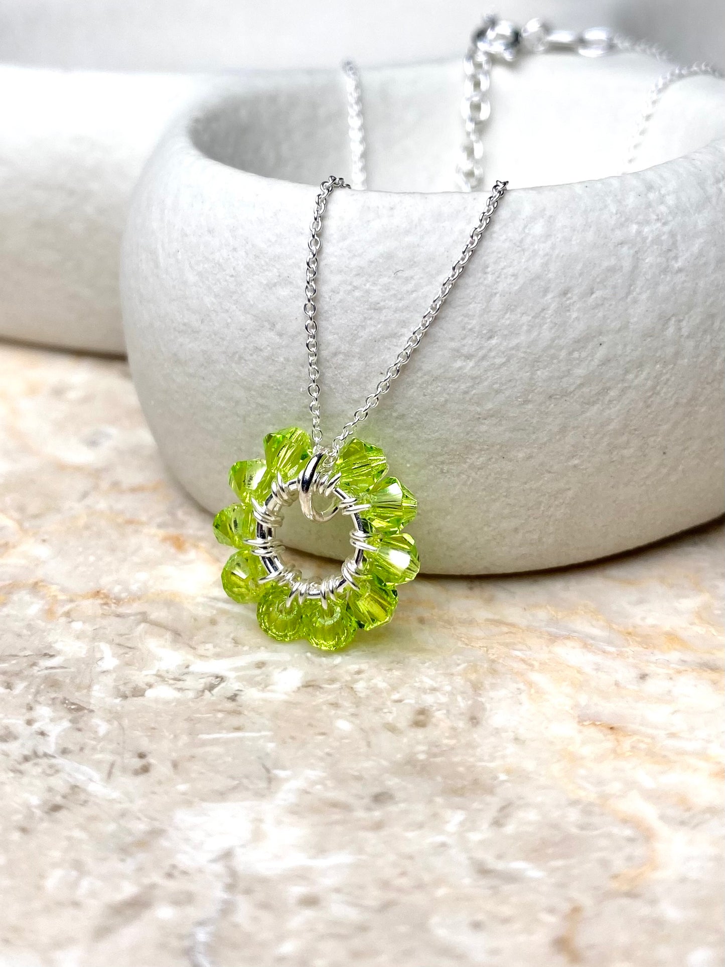 Värikäs ja siro hopeinen kaulakoru, joka on koristeltu limen värisillä kristalleilla