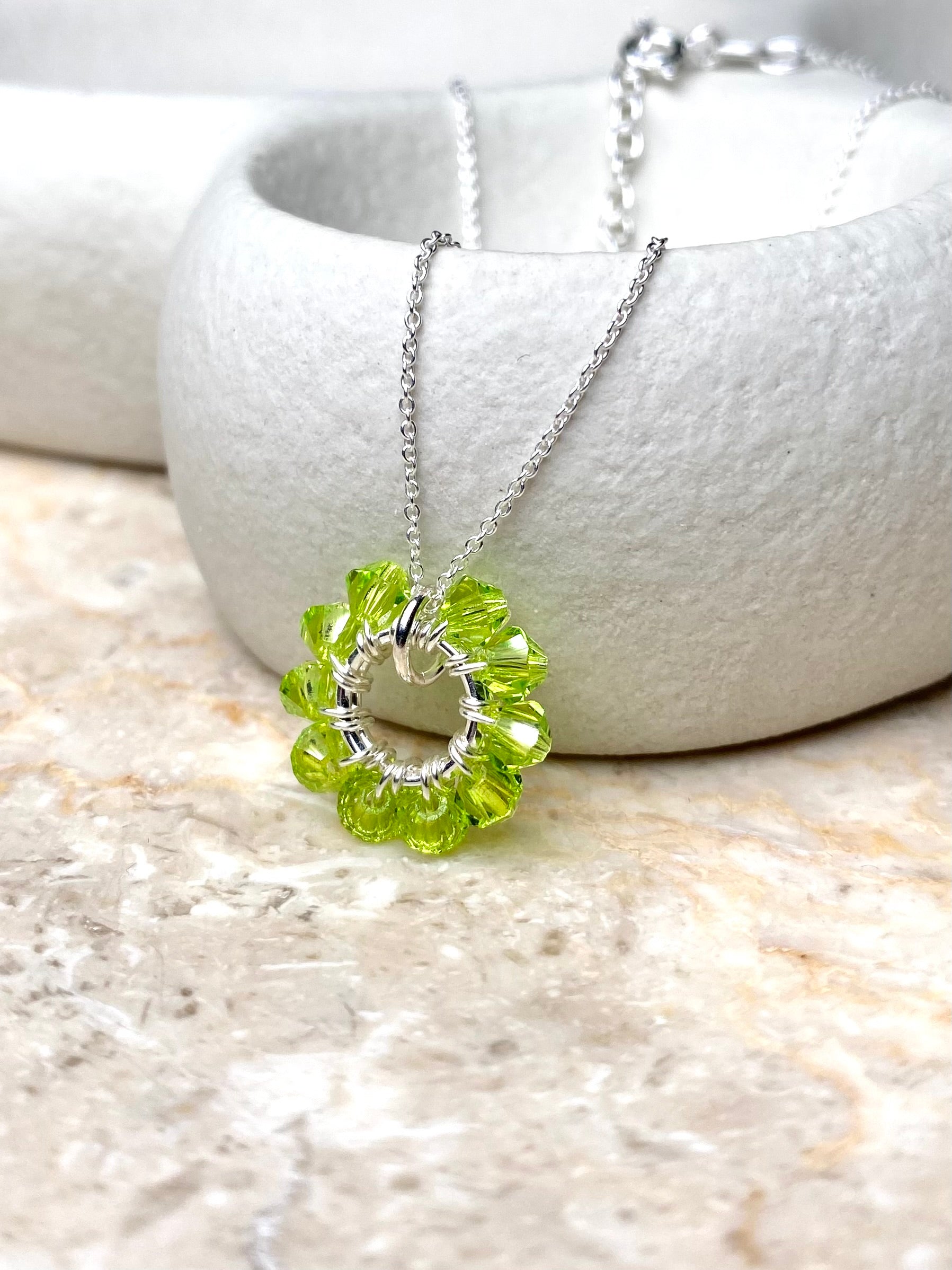 Värikäs ja siro hopeinen kaulakoru, joka on koristeltu limen värisillä kristalleilla