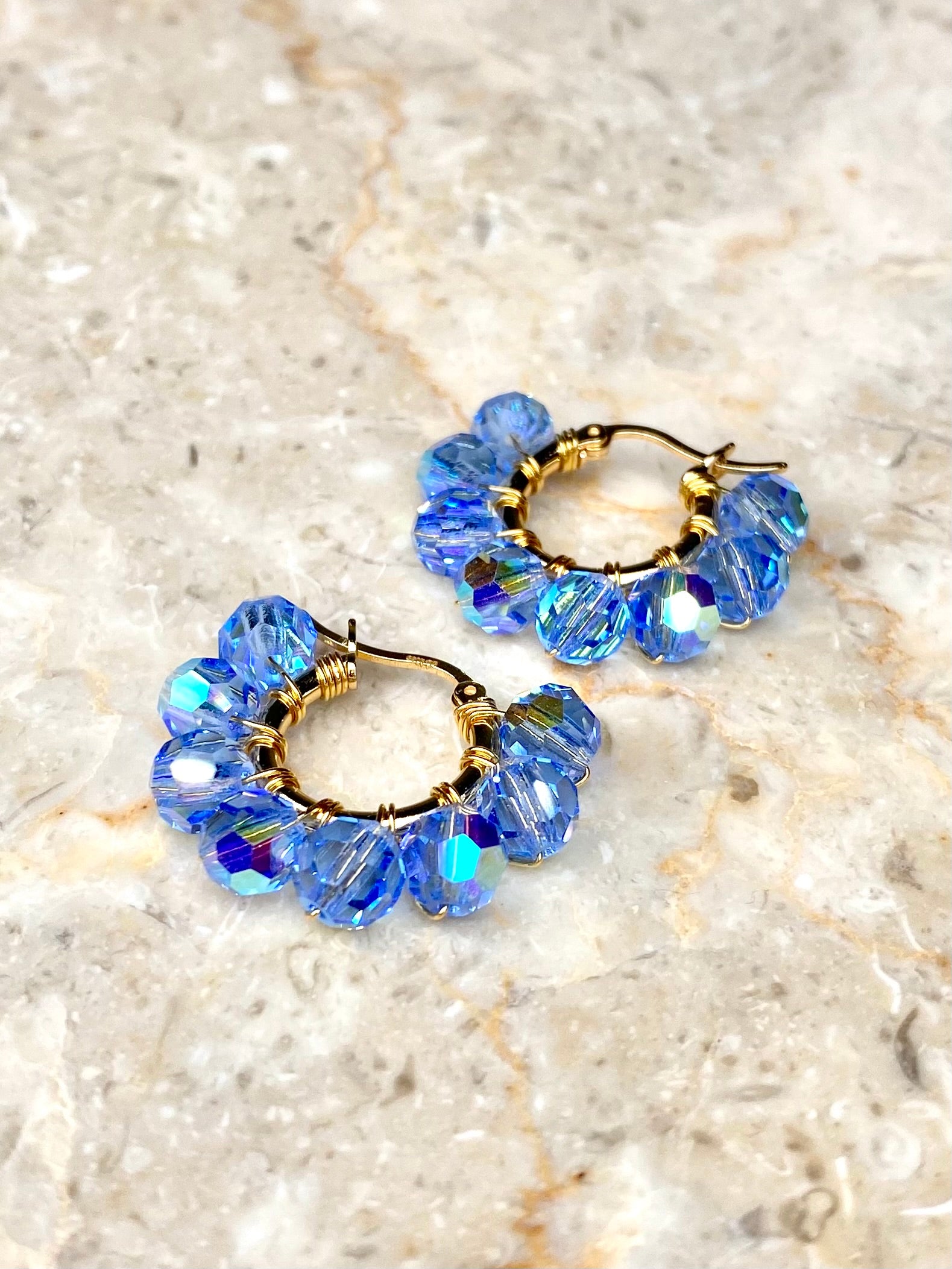 Pienet vaaleansiniset korvakorut, jotka on käsintehty kullatusta hopeasta