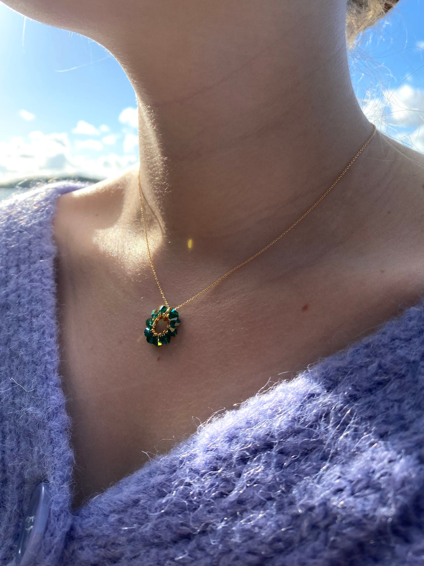 Siro kultainen kaulakoru tummanvihreällä riipuksella mallin kaulassa