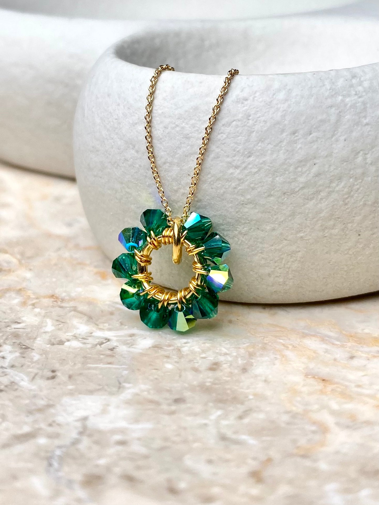 Lähikuva sirosta ja yksinkertaisesta vihreästä kaulakorusta, joka on tehty kullatusta hopeasta.