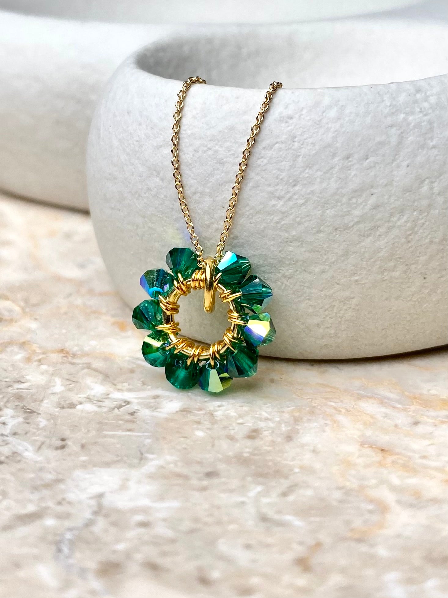 Lähikuva sirosta ja yksinkertaisesta vihreästä kaulakorusta, joka on tehty kullatusta hopeasta.