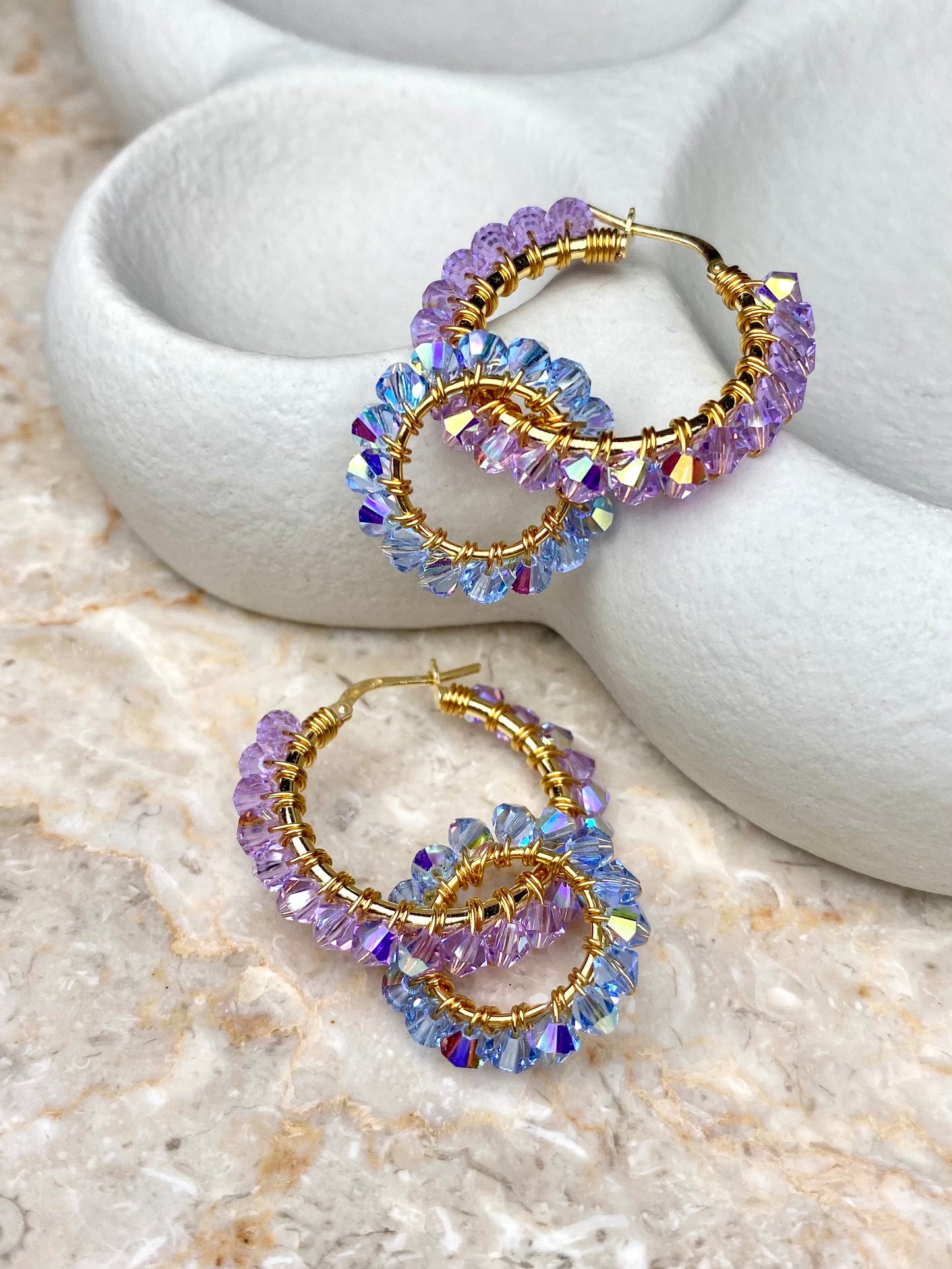 Kullatut hopeakorvakorut, joissa on värikkäitä kristalleja violetin ja sinisen sävyissä