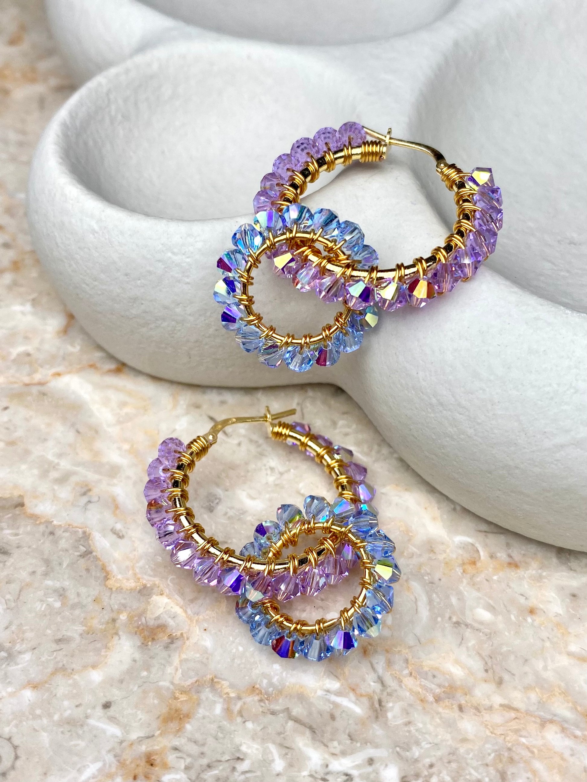 Kullatut hopeakorvakorut, joissa on värikkäitä kristalleja violetin ja sinisen sävyissä