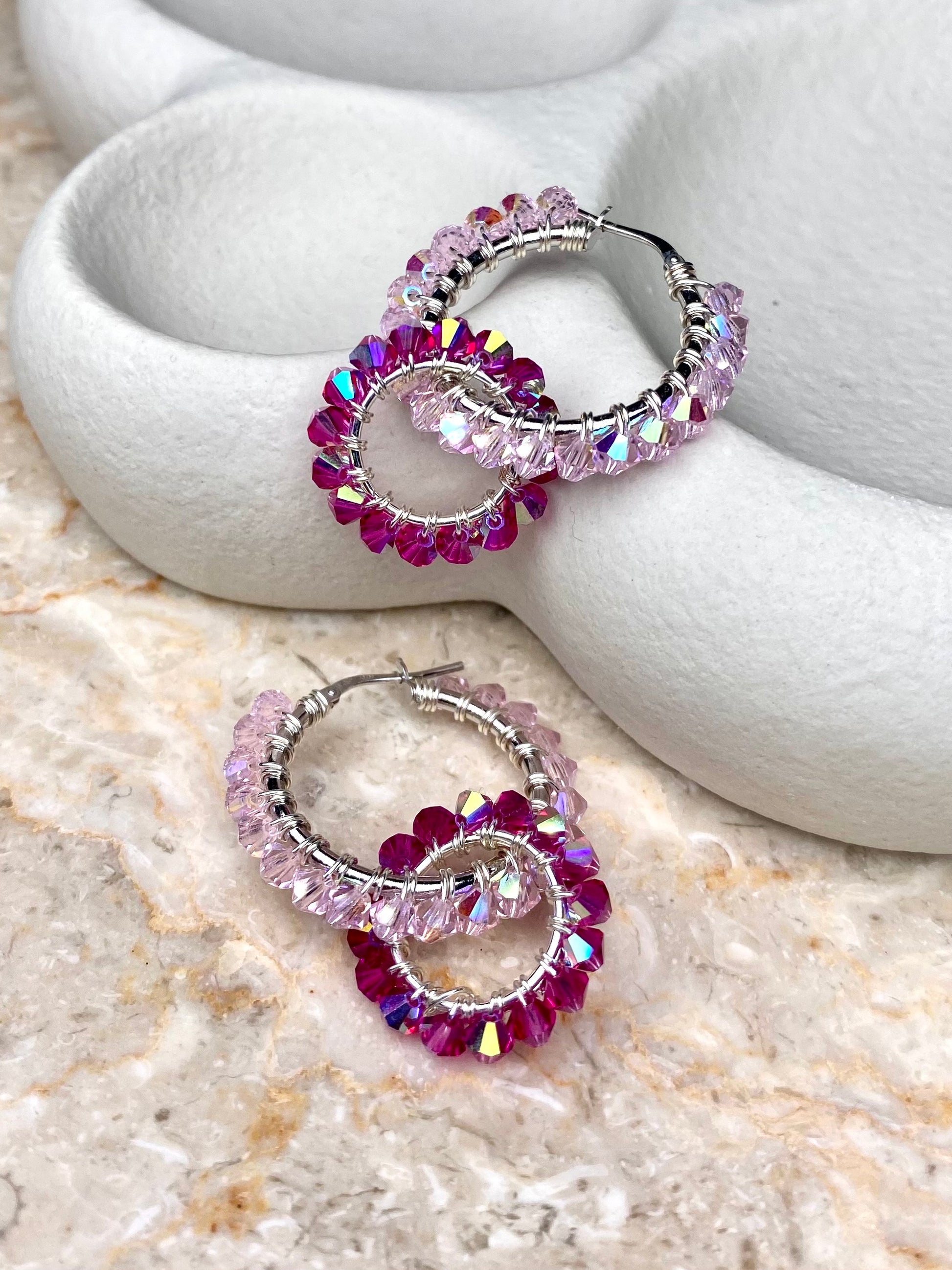 Pinkit hopeiset rengaskorvakorut, joissa on näyttävä muotoilu ja kimaltavat kristallit