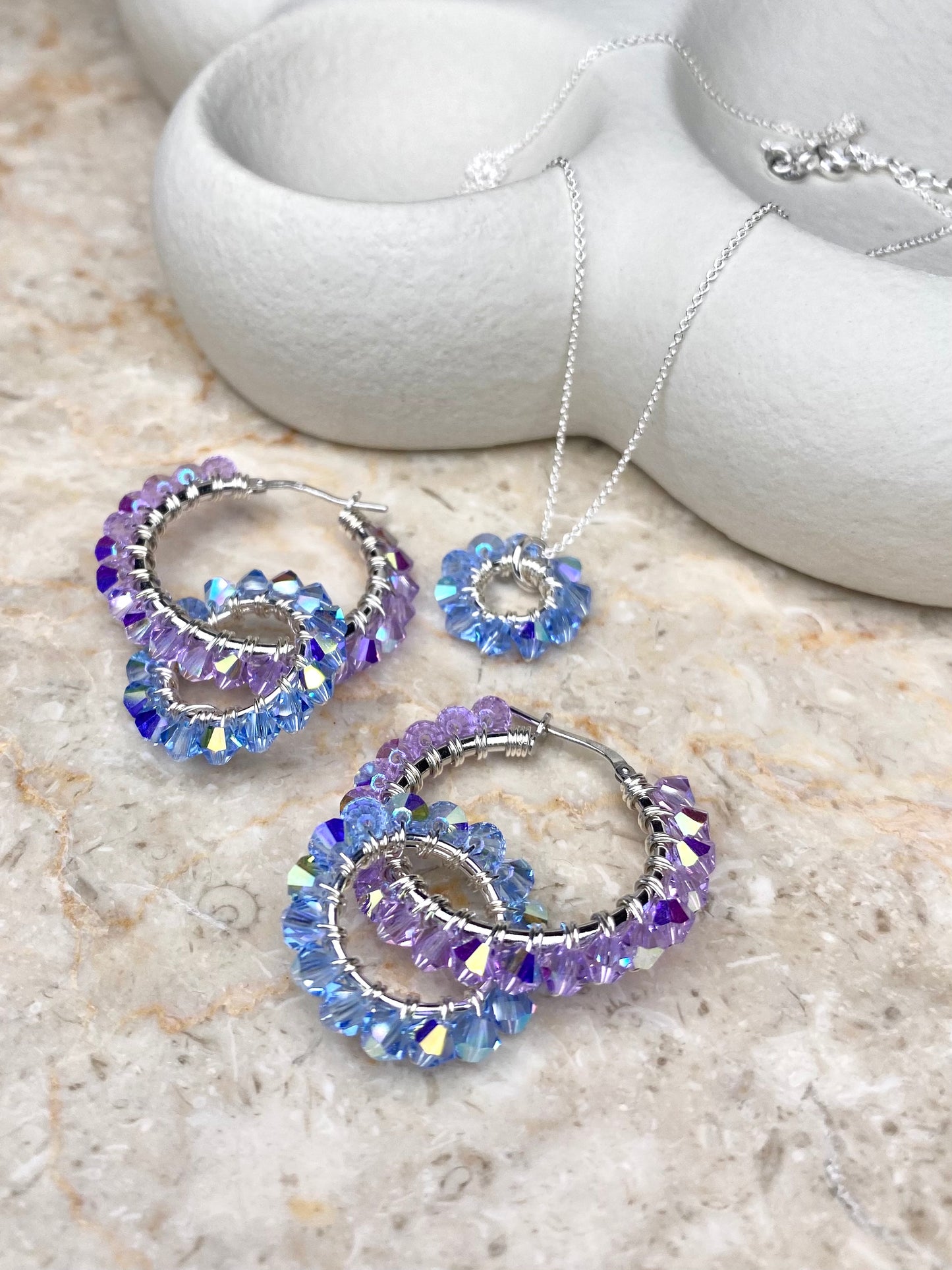 Hopeinen vaaleansininen ja lila korusetti, jossa on yhteensopivat korvakorut ja kaulakoru